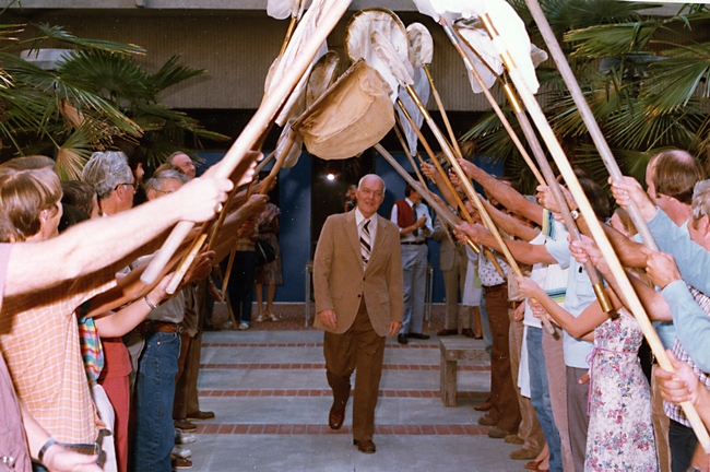Professor Richard M. Bohart (1913-2007) walks through the archway of a 21-insect salute in 1986.