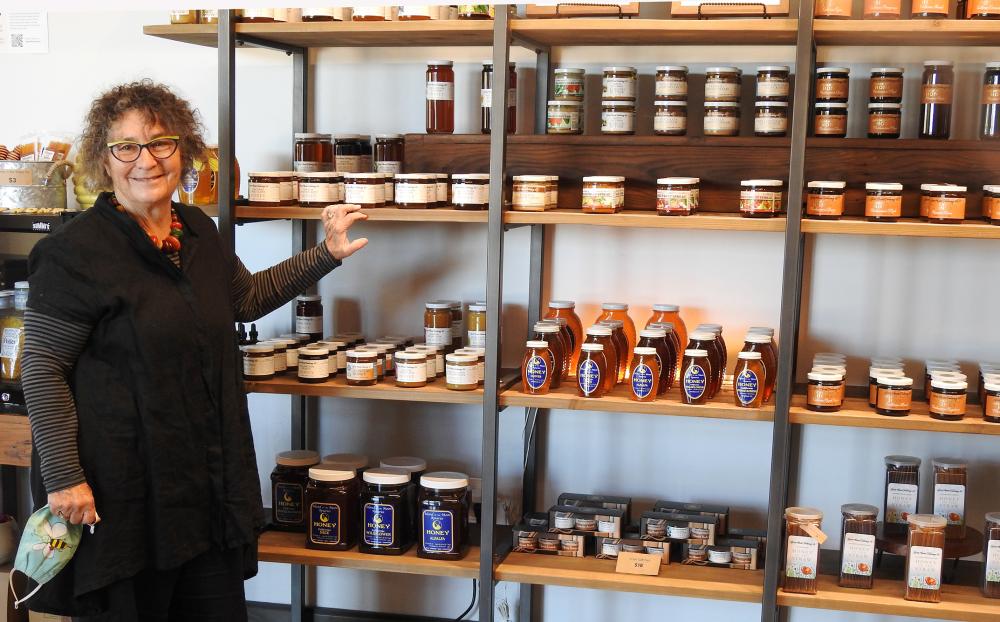 Amina Harris stands next to jars of honey in her business, The Hive.