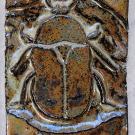 This design shows a scarab beetle on a background of geometric triangles and diamonds.